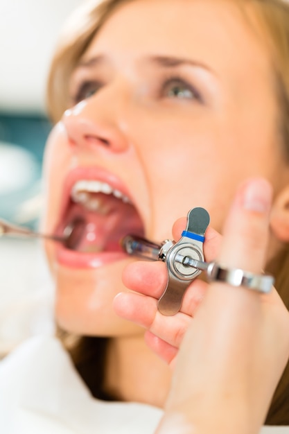 Foto dentista sosteniendo una jeringa y anestesiando a su paciente