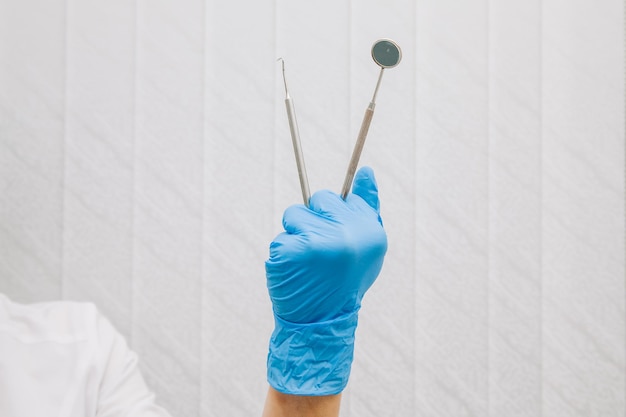 Foto el dentista sostiene en sus manos instrumentos dentales, vestido con guantes azules, primer plano. odontología