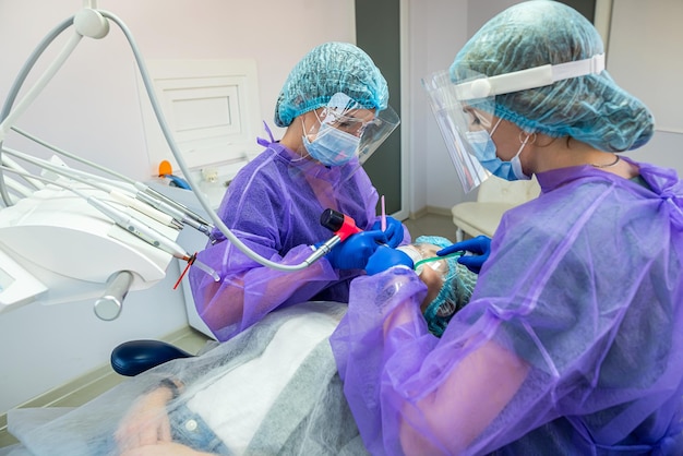 Un dentista y su asistente realizan la operación en la oficina para instalar un implante dental