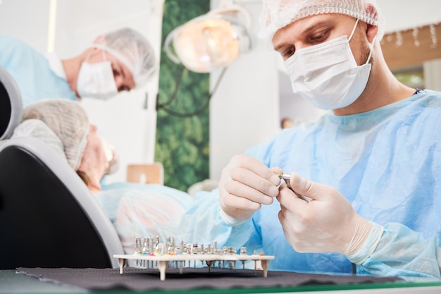 Dentista y su asistente trabajando con un paciente en una silla de dentista en la oficina del dentista