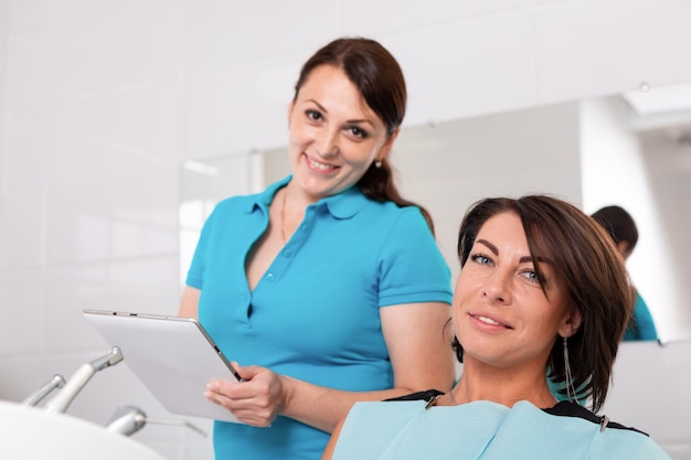 El dentista y su paciente feliz miran a la cámara y sonríen. Recepción en el dentista, dientes sanos, paciente feliz, dientes bonitos.