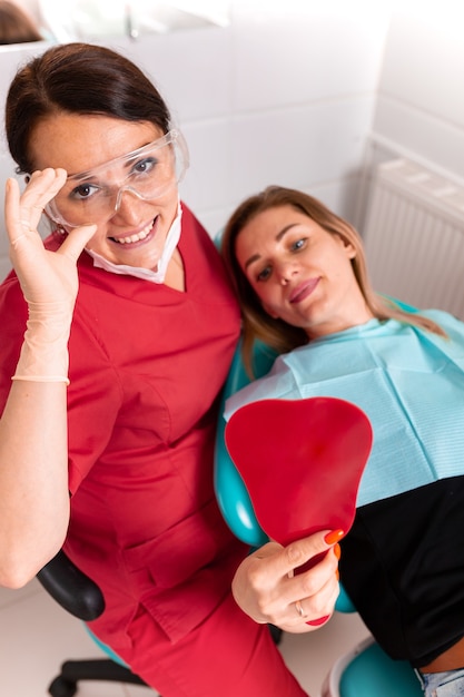 El dentista y su paciente feliz miran a la cámara y sonríen. Recepción en el dentista, dientes sanos, paciente feliz, dientes bonitos.