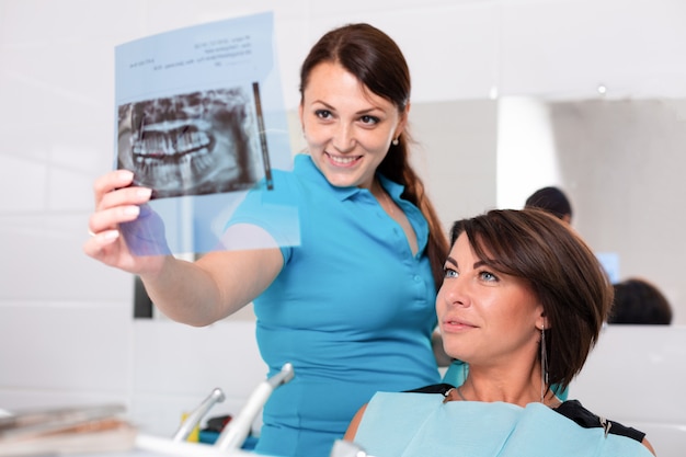 Dentista terminando con éxito la restauración de los dientes, médico de cabello negro, con máscara verde