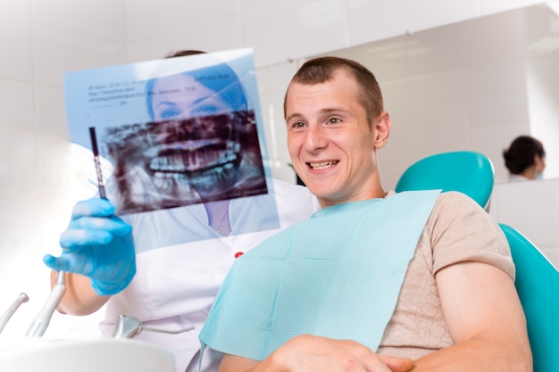 Dentista terminando con éxito la restauración de los dientes, médico de cabello negro, con máscara verde