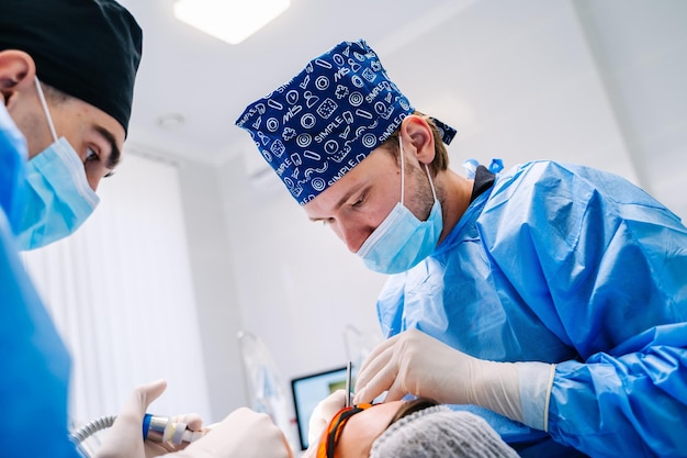 El dentista tiene instrumentos médicos específicos para examinar al paciente. Dos dentistas en clínica dental con clienta.