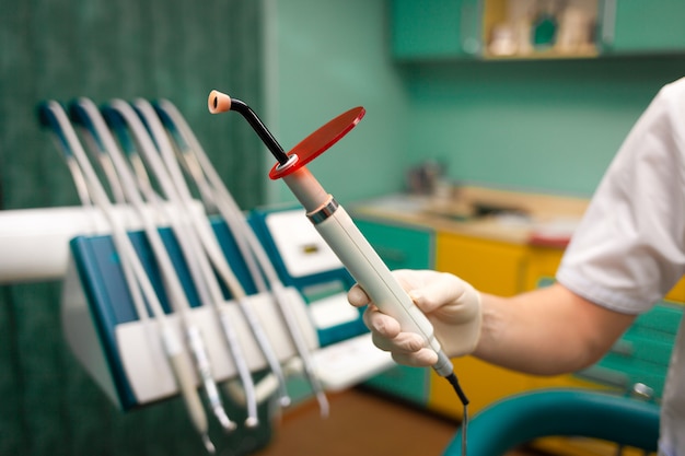 El dentista tiene en la mano una lámpara ultravioleta para blanquear los dientes