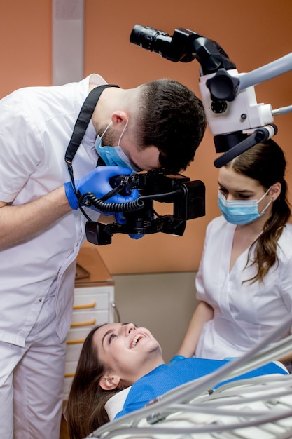 El dentista toma fotografías de los dientes del paciente después del tratamiento.