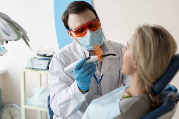 Dentista trabajando con cliente en silla