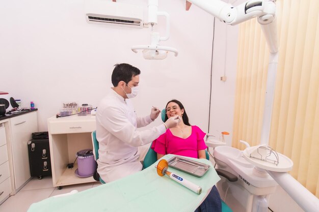 Dentista trabajando en su paciente femenina en su consultorio dental.