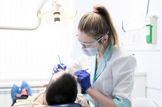 Dentista en el trabajo en la oficina. Oficina de luz, médico joven