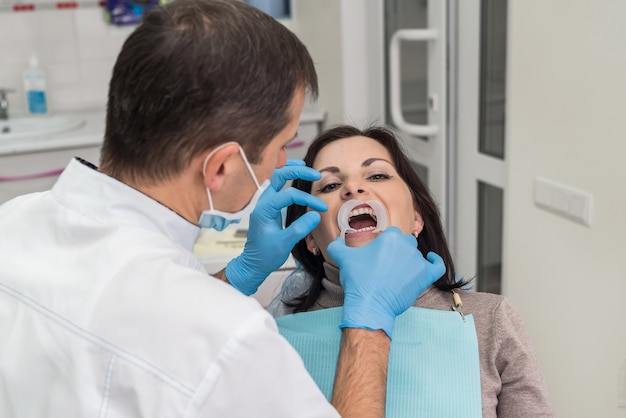 Foto dentista trabalhando com paciente em consultório dentário