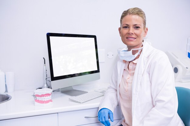 Foto dentista trabalhando sentado em frente ao computador na clínica médica