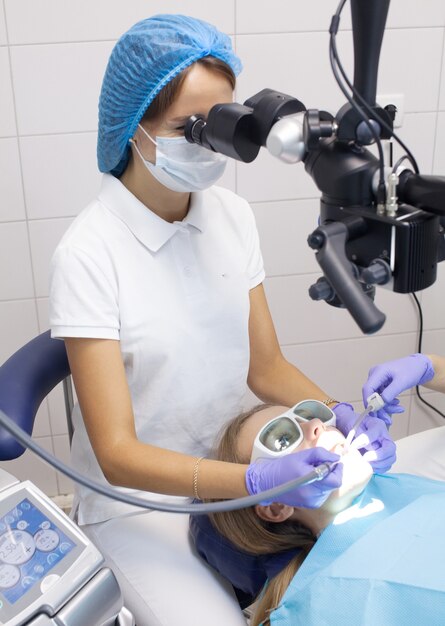 El dentista trata los dientes de una hermosa joven paciente