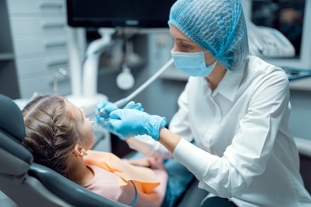 La dentista trata los dientes de la niña paciente en el consultorio dental concepto de odontología