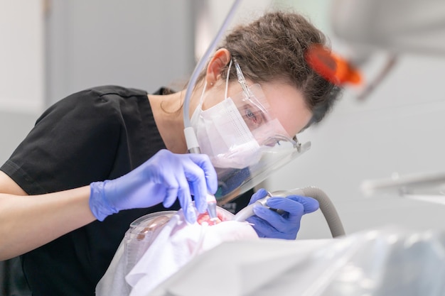 Una dentista trata los dientes de un paciente con caries utilizando instrumentos dentales