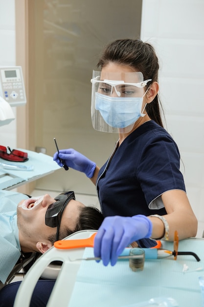 Foto el dentista trata los dientes del paciente.