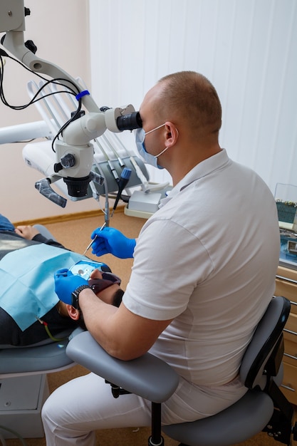 El dentista trata los dientes de su paciente con un microscopio. El dentista trata la boca del paciente. Cuidado dental. Foto de alta calidad