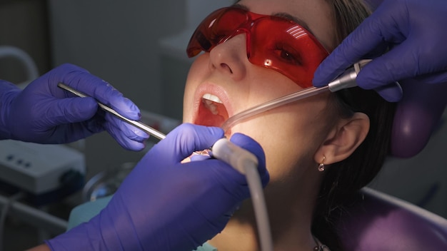 Dentista tratando dentes para paciente mulher na clínica, close-up