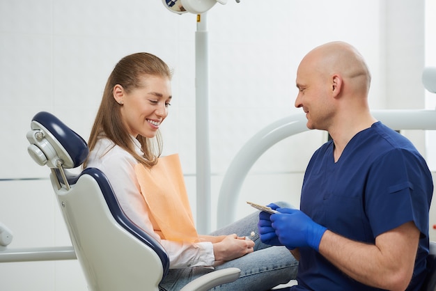 dentista en un uniforme y guantes médicos desechables con un paciente en el consultorio del dentista