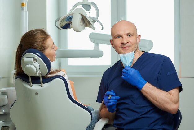 dentista en un uniforme y guantes médicos desechables con un paciente en el consultorio del dentista