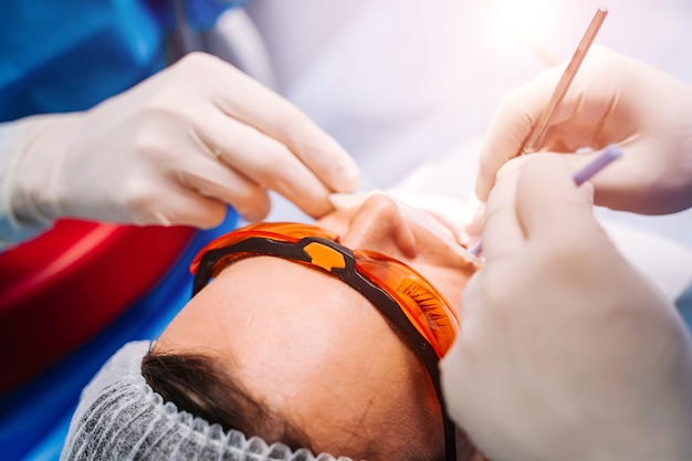 Dentista en uniforme realiza tratamiento dental en un paciente en la oficina de estomatología moderna.