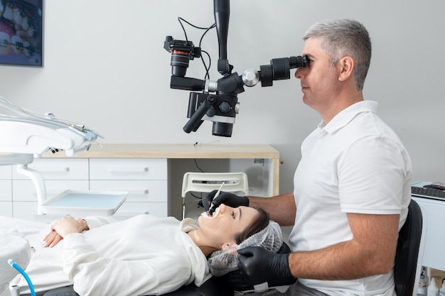 Dentista usando microscópio odontológico tratando os dentes do paciente no consultório da clínica odontológica Medicina odontologia e conceito de saúde Equipamento odontológico