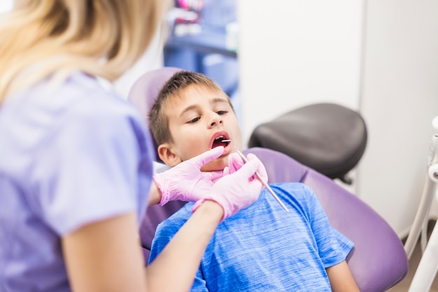 Dentista, verificando os dentes do menino na clínica