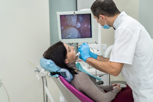 Dentista verificando os dentes do paciente com a câmera em estomatologia