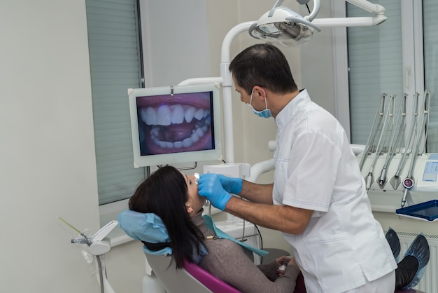 Dentista verificando os dentes do paciente com a câmera em estomatologia