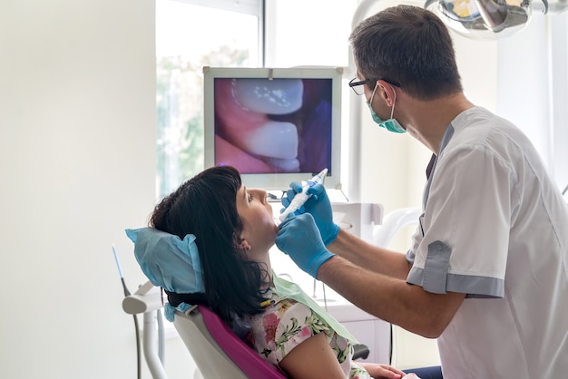 Dentista verificando os dentes do paciente com câmera intraoral