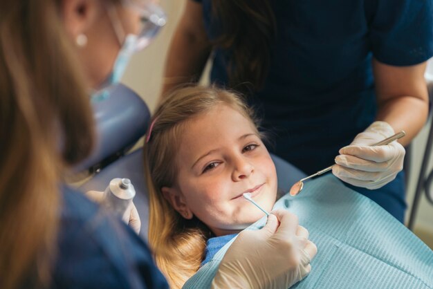 Dentistas com paciente durante intervenção odontológica em menina. conceito dentista