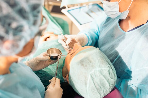 Dentistas com um paciente durante uma intervenção odontológica. Conceito Médico.