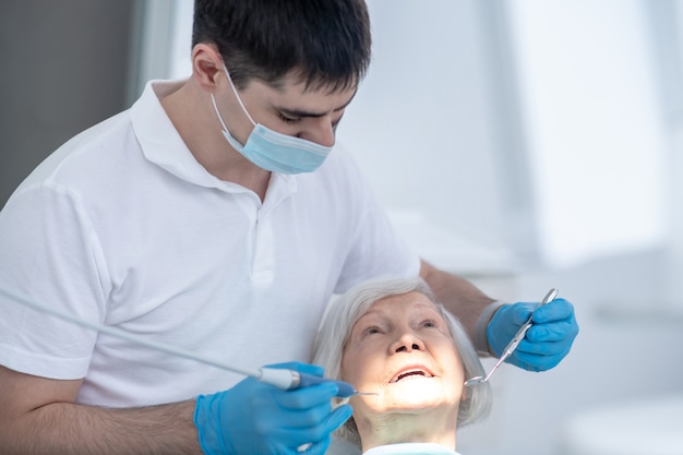 En los dentistas. Dentista masculino que trabaja con un paciente mayor con enfermedad periodental