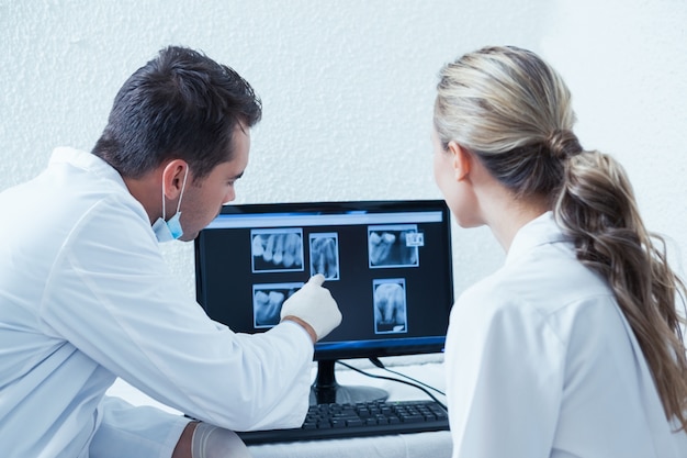 Dentistas mirando rayos x en la computadora