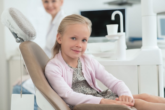En los dentistas. Una niña visitando al dentista y sintiéndose emocionada.