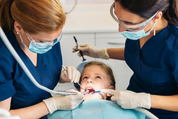 Dentistas con un paciente durante una intervención dental a niña.