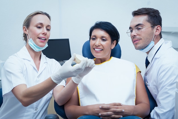 Dentistas que muestran dientes de prótesis de mujer