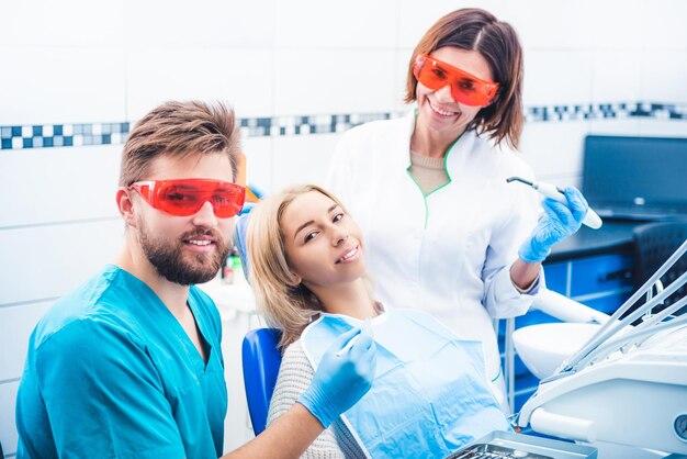 Dentistas sonrientes con paciente en clínica de estomatología