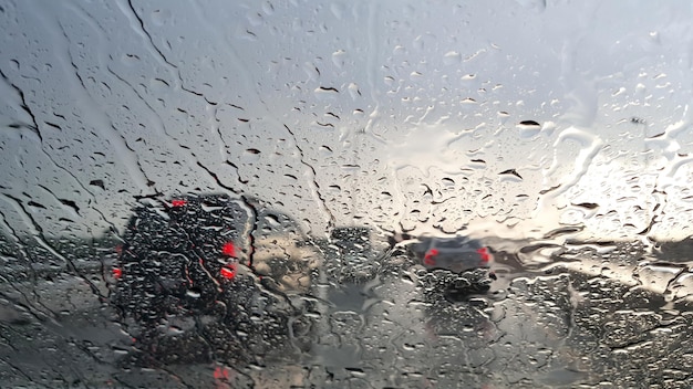 Dentro del coche. Gotas de agua de lluvia de primer plano. vista del parabrisas del camión durante el día lluvioso en la carretera por la noche