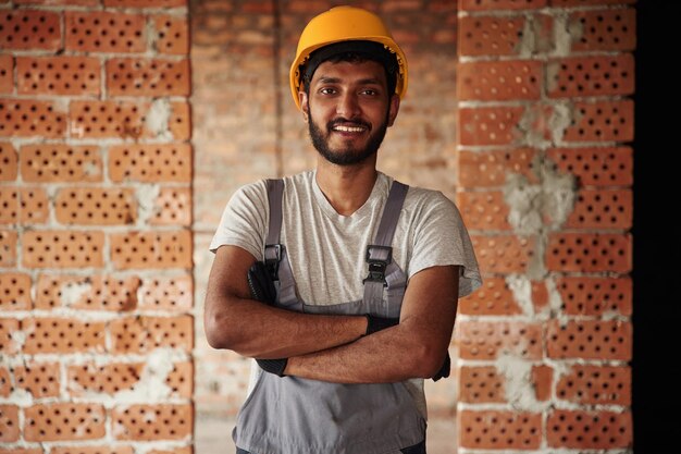 Dentro de casa, contra uma parede de tijolos, um belo indiano está no local de construção.