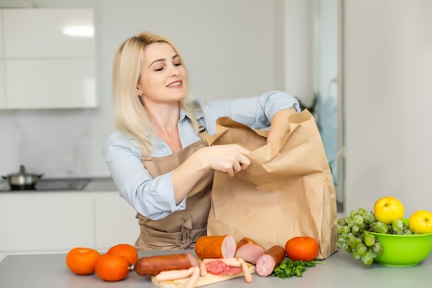 Dentro de casa. Jovem desempacotando a lancheira na cozinha