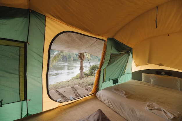 Dentro de una gran tienda de campaña cómoda en un camping en el bosque tropical junto al río de vacaciones