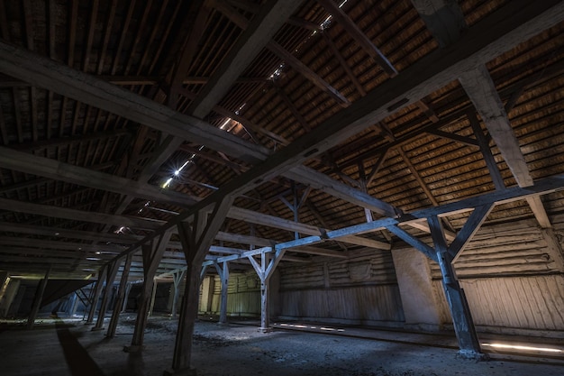 Dentro de un hangar de madera en ruinas abandonado oscuro con columnas podridas