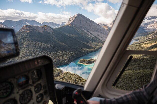 Dentro del helicóptero volando sobre las montañas rocosas con lago colorido