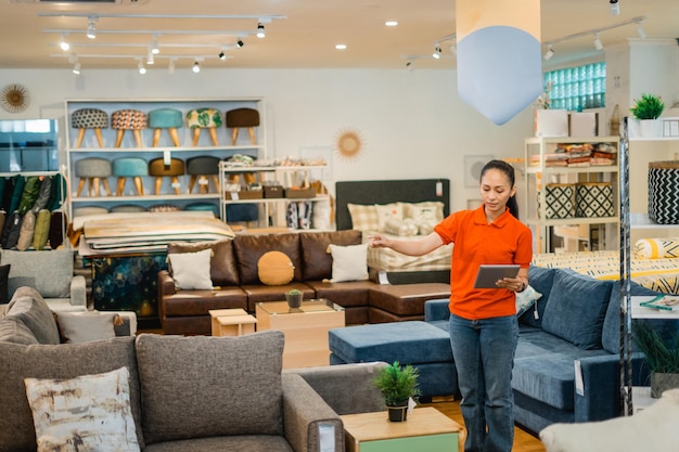 Foto dependienta femenina comprobando datos en una tableta mientras trabajaba en una tienda de muebles