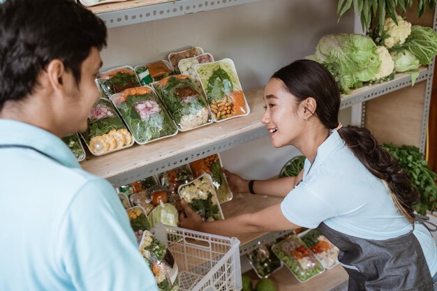 Los dependientes femeninos y masculinos ponen verduras envasadas