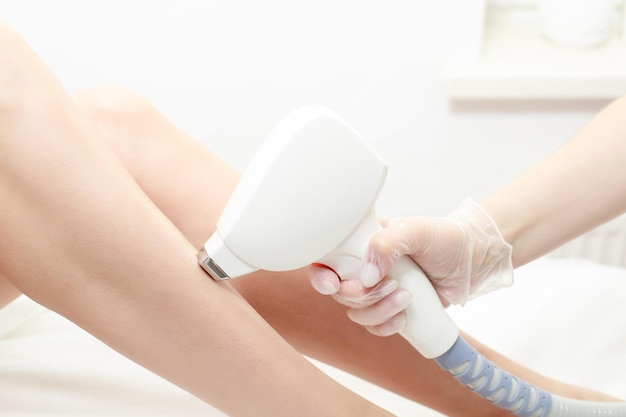 Depilação a laser de diodo Esteticista remove pêlos em belas pernas femininas procedimento a laser no estúdio de beleza ou clínica Tratamento de depilação de cuidados com o corpo Depilação para pele lisa