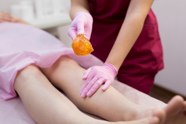 Depilación de azúcar de los pies en el salón de belleza. Deshacerse del pelo en las piernas.