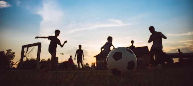 Deporte de acción de silueta al aire libre de niños divirtiéndose jugando al fútbol