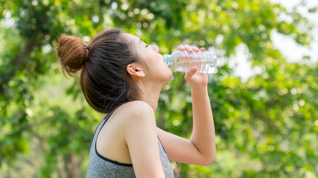 Deporte asiático lindo ajuste saludable y firme adolescente delgada bebe agua de botella de plástico